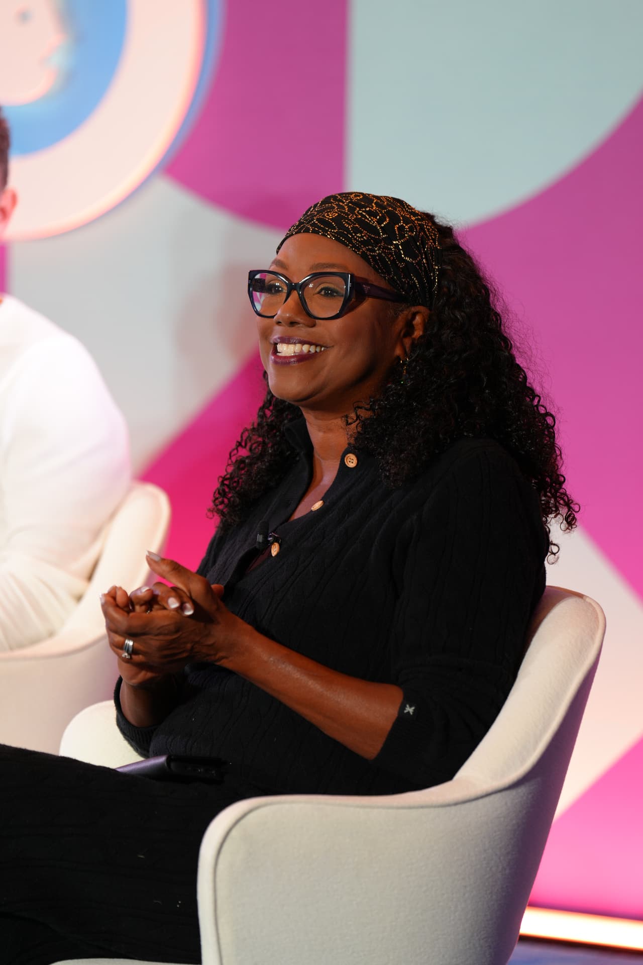 Wendy Calhoun smiling and clapping toward the audience at Advertising Week New York, in the original three-quarter seated portrait